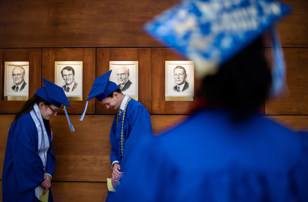 two students bowing to each other so their graduation tassels swing