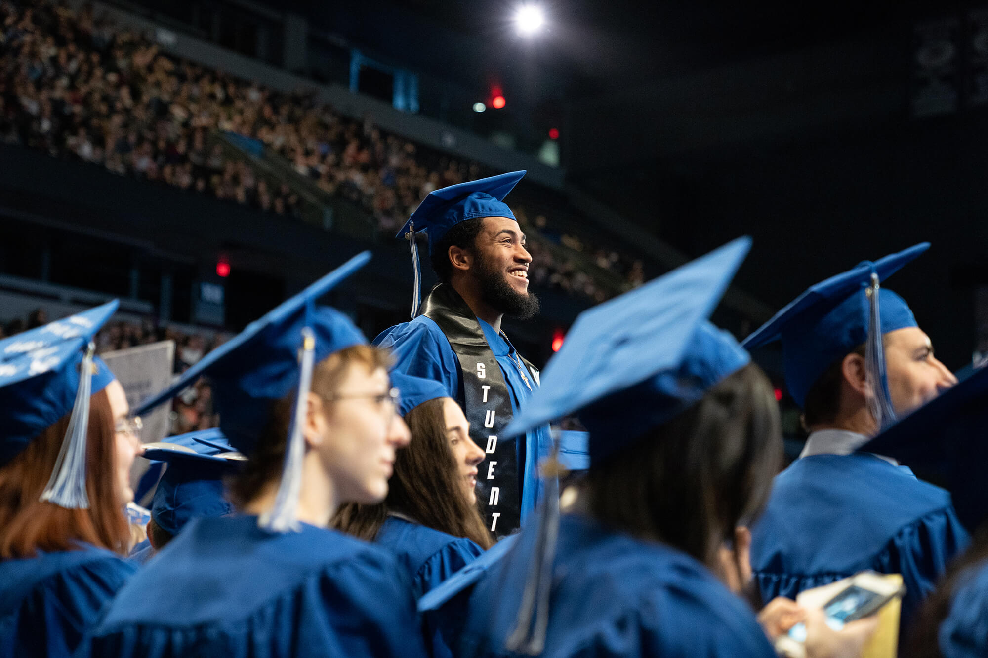 a student stands up in the audience during commencement