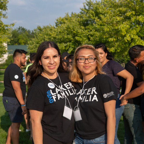 Two people pose together outdoors with black shirts on that read 'Laker Familia'