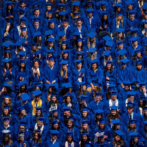 A view from above of graduates in blue gowns sitting.