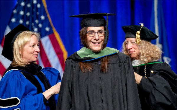 Founder of Epic Systems Judith R. Faulkner is hooded by Provost Jennifer Drake, right, and Tina Freese Decker, CEO of Corewell Health, while receiving an honorary degree during Commencement at Van Andel Arena on May 2.