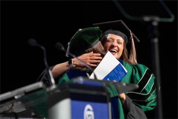 Student Commencement speaker Sarah Dudinetz embraces Vice President for Student Affairs Jenny Hall-Jones after receiving her Master of Business Administration at Grand Valley State University's afternoon Commencement on May 2.