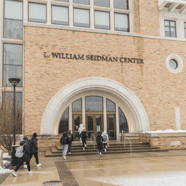 Students walk toward the arched entrance of the L. William Seidman Center on Grand Valley State University�s campus during light snowfall.