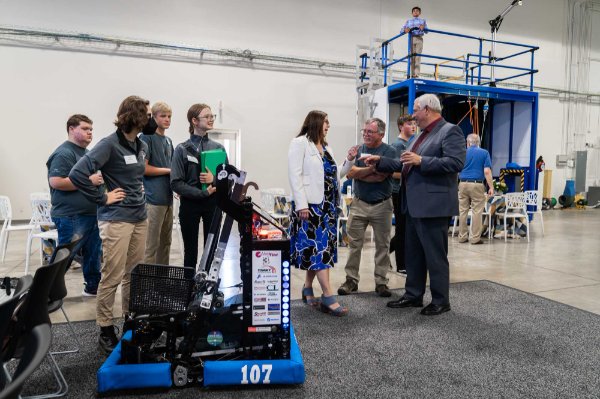 students stand by a robot while others talk off to the right