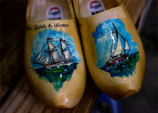 a pair of painted wooden shoes, left shoe says Caleb Ulman