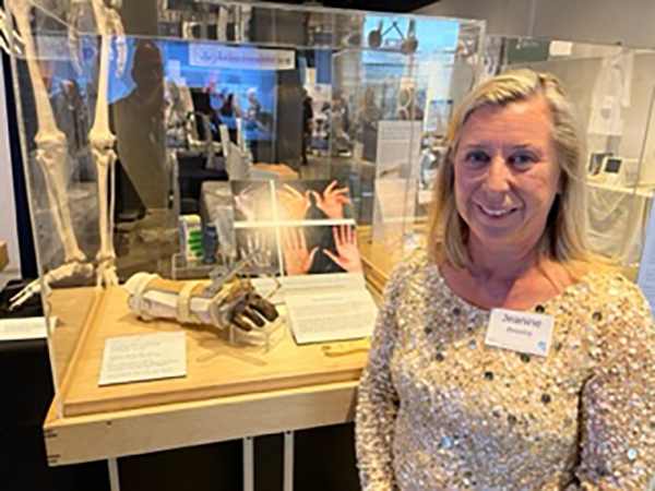 woman standing in front of museum exhibit case with model of hand brace in it