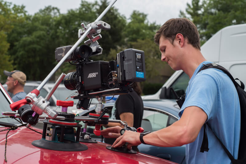 Key grip Austin Stuk attaching the car mount for a camera onto a pickup truck.