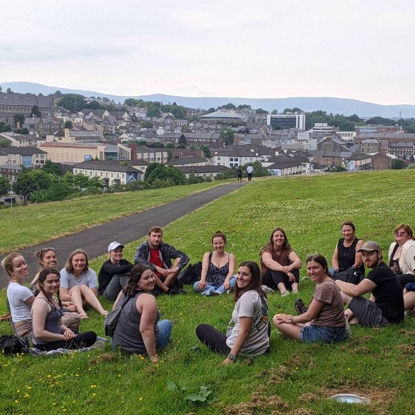 group of students seated in a circle on a hill with northern Ireland in the distance