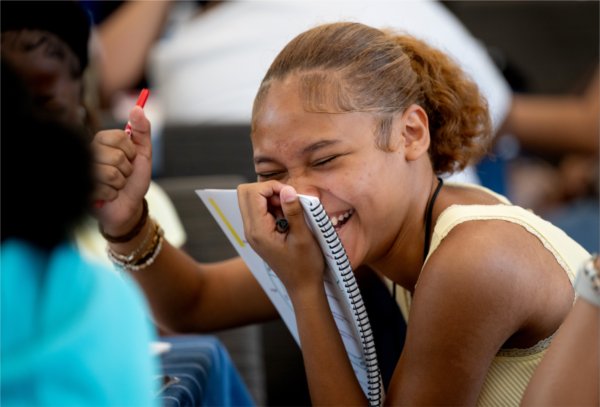  A high school student laughs into her notebook after answering a question. 