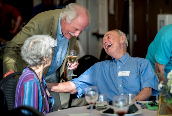  Three people share a laugh while at a celebratory dinner event. 