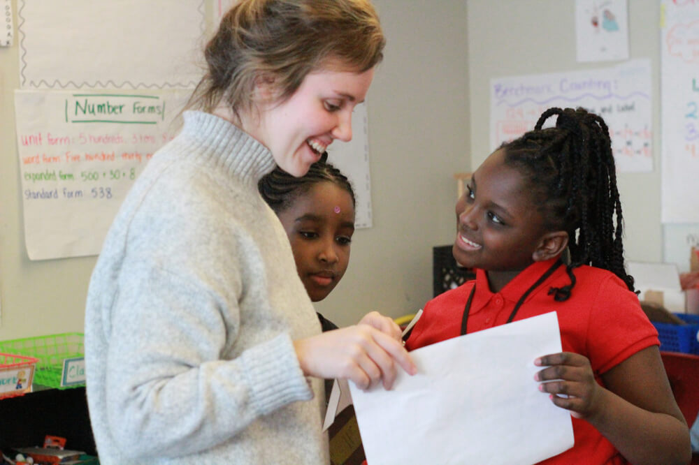 A teacher looks over the paper of a student in her classroom.