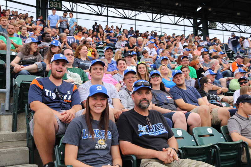 Group of fans smiling, watching the baseball game