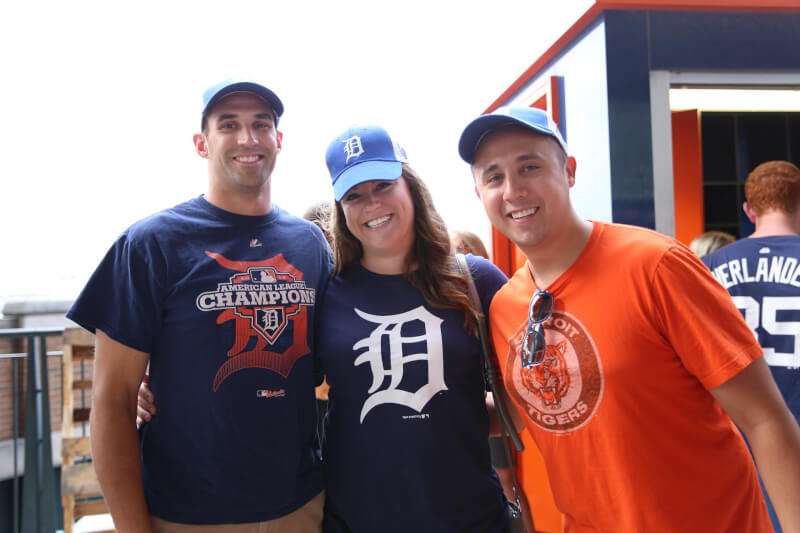  Three alumni wearing Detroit Tigers shirts hugging and smiling