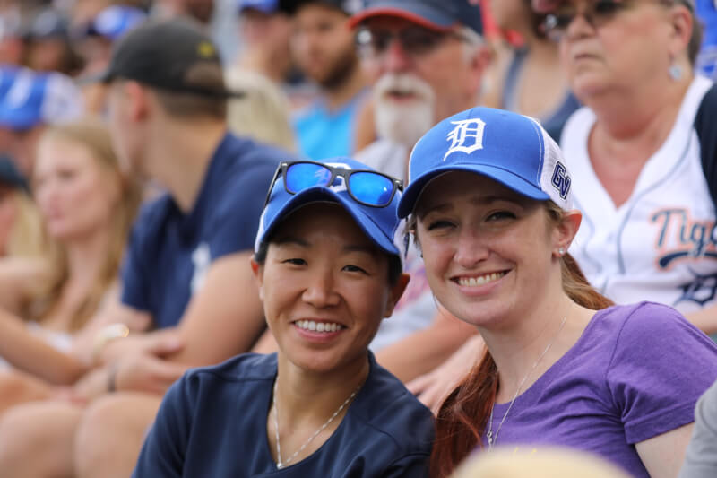 Two female alumni smiling while wearing Detroit Tigers hats