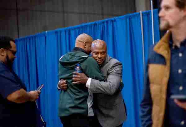 Cornell Mann, right, hugs Mark Montgomery, assistant basketball coach at Michigan State University, following the news conference introducing Mann as Grand Valley's next men's head basketball coach.
