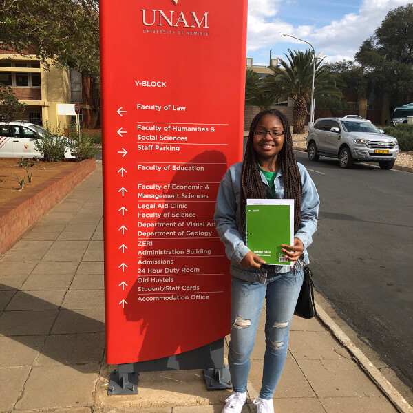 student standing in front of sign at African university