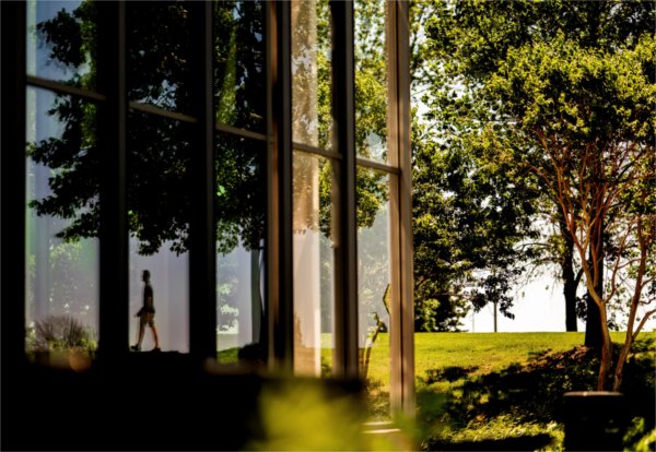 A person is reflected in the Mary Idema Pew Library windows on June 12.