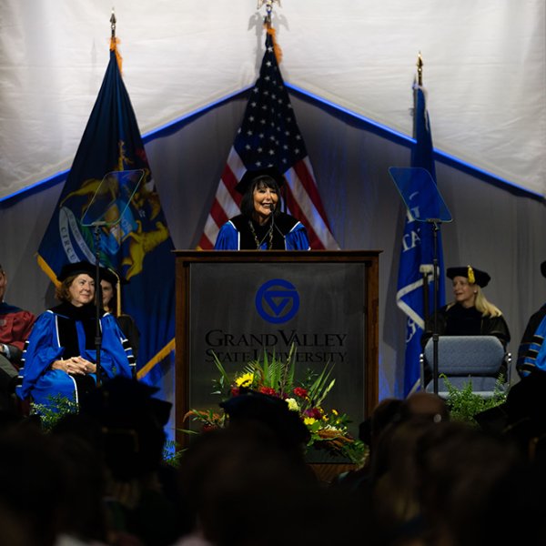 President Mantella and the platform party on stage during convocation, flags in the background, and banners hanging down