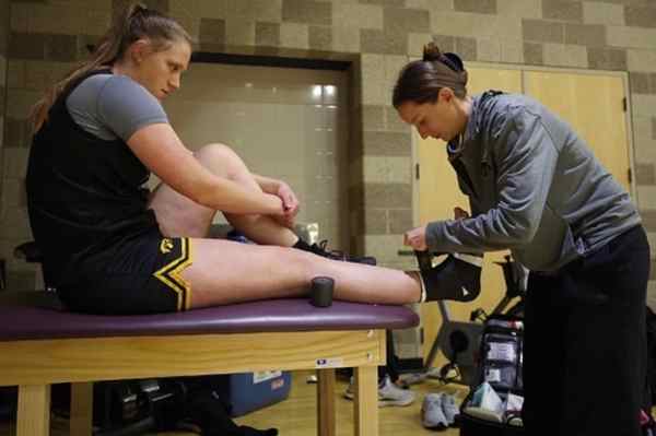 Andrea Chilcote, '12, tapes the ankle of an Iowa basketball player. 