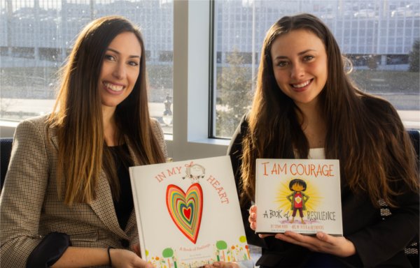 two women seated holding children's books