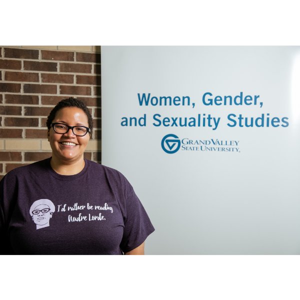 Ayana Weekley standing beside sign that reads Women, Gender, and Sexuality Studies with GVSU wordmark underneath