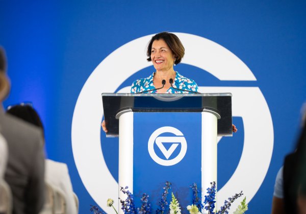 A person standing at a podium smiles while giving a speech.