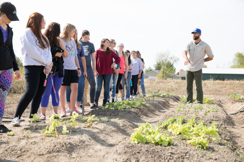 garden, with plants growing, man talking to people standing 
