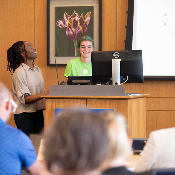 two women standing in front of room giving presentation