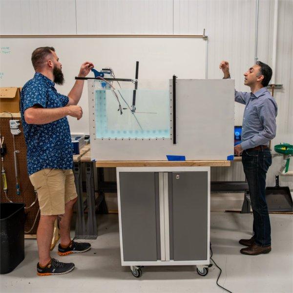 two people standing on either side of a large water tank