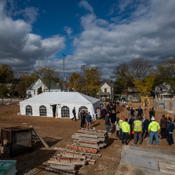 People gathered near a white tent for the groundbreaking ceremony at the corner of Trowbridge and Lafayette.