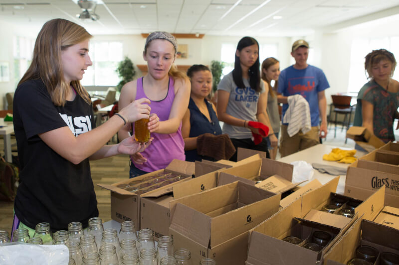  Members of the student organization GVSU Beekeepers bottle honey.