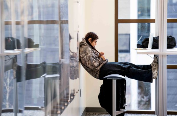 A college student props their legs up as they listen to their online class on a laptop computer. 