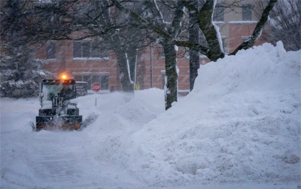 A person in a machine clears snow from university sidewalks.  