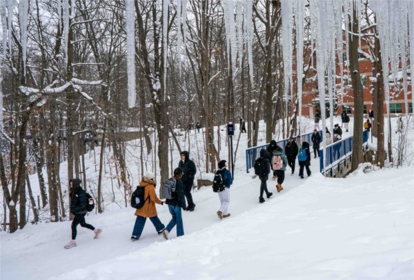  A line of students walk near icicles on a snowy college campus