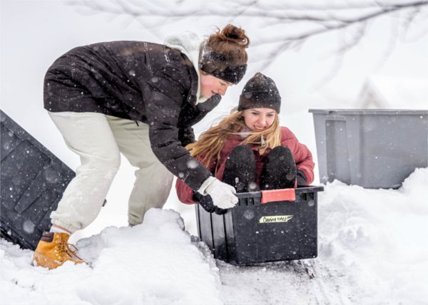  College students help each other as they use rubber tubs as sleds. 