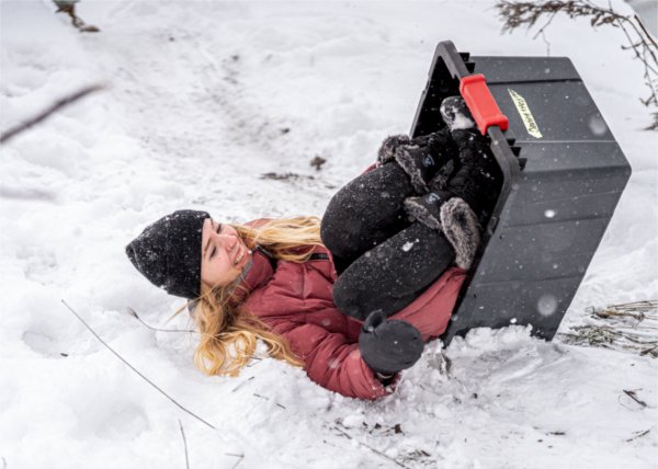  A college student laughs as they tip over in their rubber tub they used as a sled. 