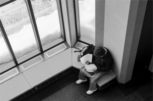  Seen from a balcony, a student sits near a window to work on schoolwork. 