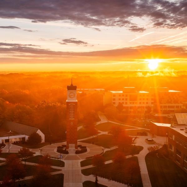 A golden sunrise highlights a university campus in fall.