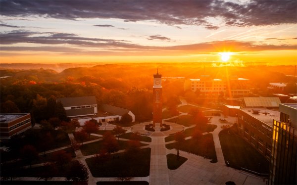 The sun rises over a college campus as seen from a drone. 