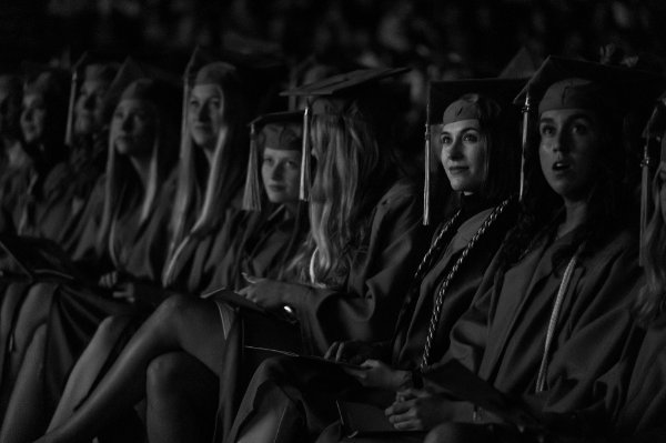  University college students sit wearing their caps and gowns during commencement. 