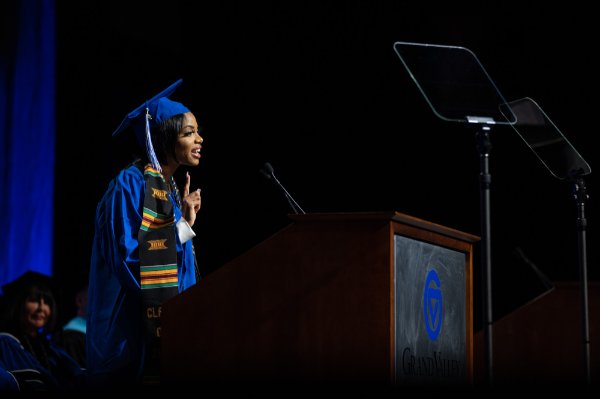  A college student speaks at the lectern in her Commencement cap and gown. 
