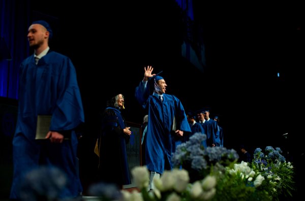  A line of college students celebrate as they cross their stage during commencement. 