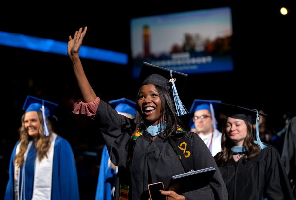  A recent college graduate waves to family as they exit the arena with a diploma.