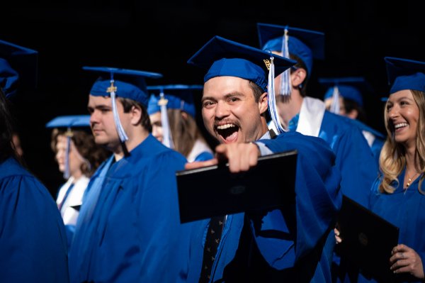   College graduates celebrate receiving their diplomas. 
