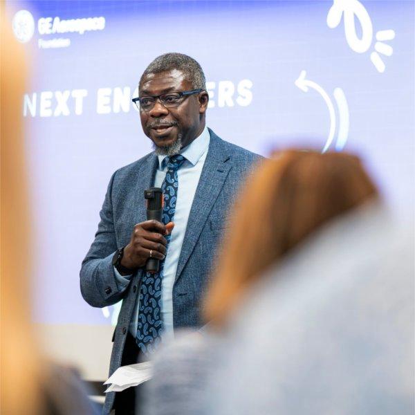 Bayo Ogundipe, dean of the Padnos College of Engineering, holds a microphone; screen behind him reads GE Aerospace Next Engineers