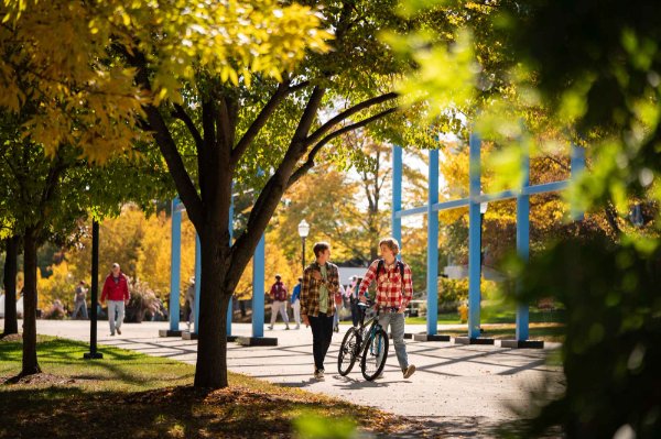  People walking through campus surrounded by colorful autumn leaves. 
