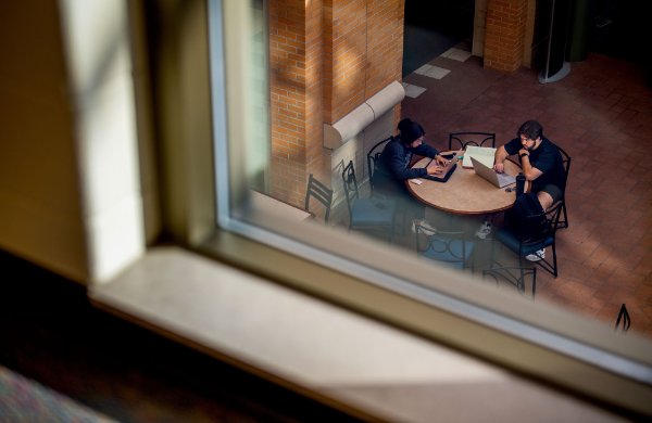  Students study at a table, viewed through a window from above. 