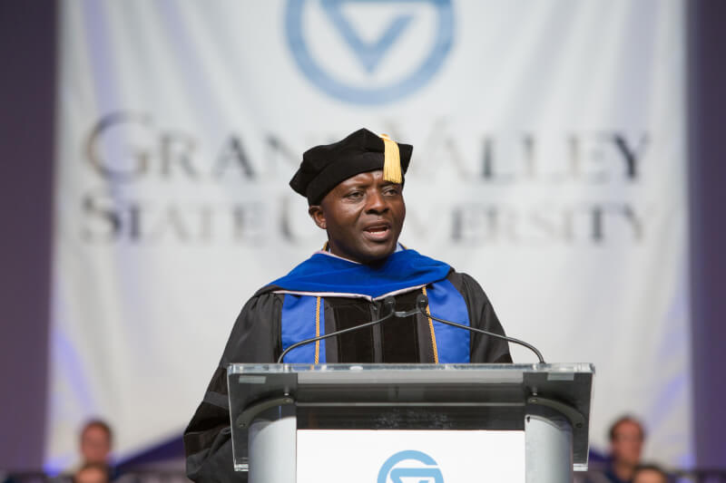 man in regalia speaking on stage