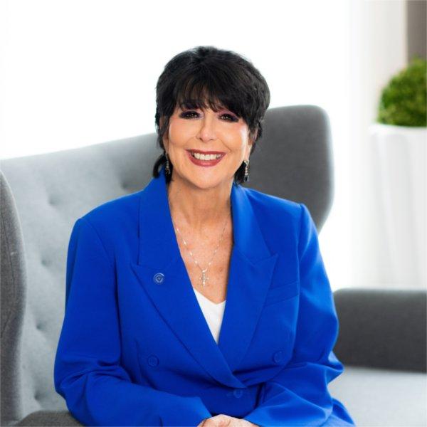 A person is seated in a chair and smiling at the camera.