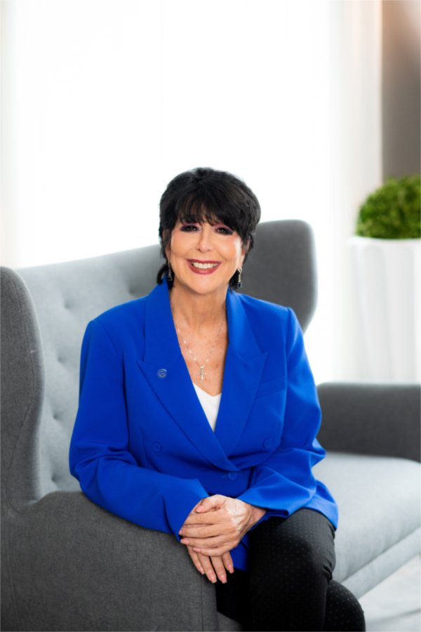 A person is seated in a chair and smiling at the camera.